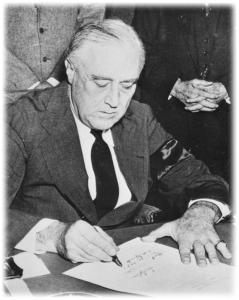 Президент Рузвельт подписывает Декларацию войны с Японией, Черная повязка на руке — символ траура по его, умершей в сентябре матери).